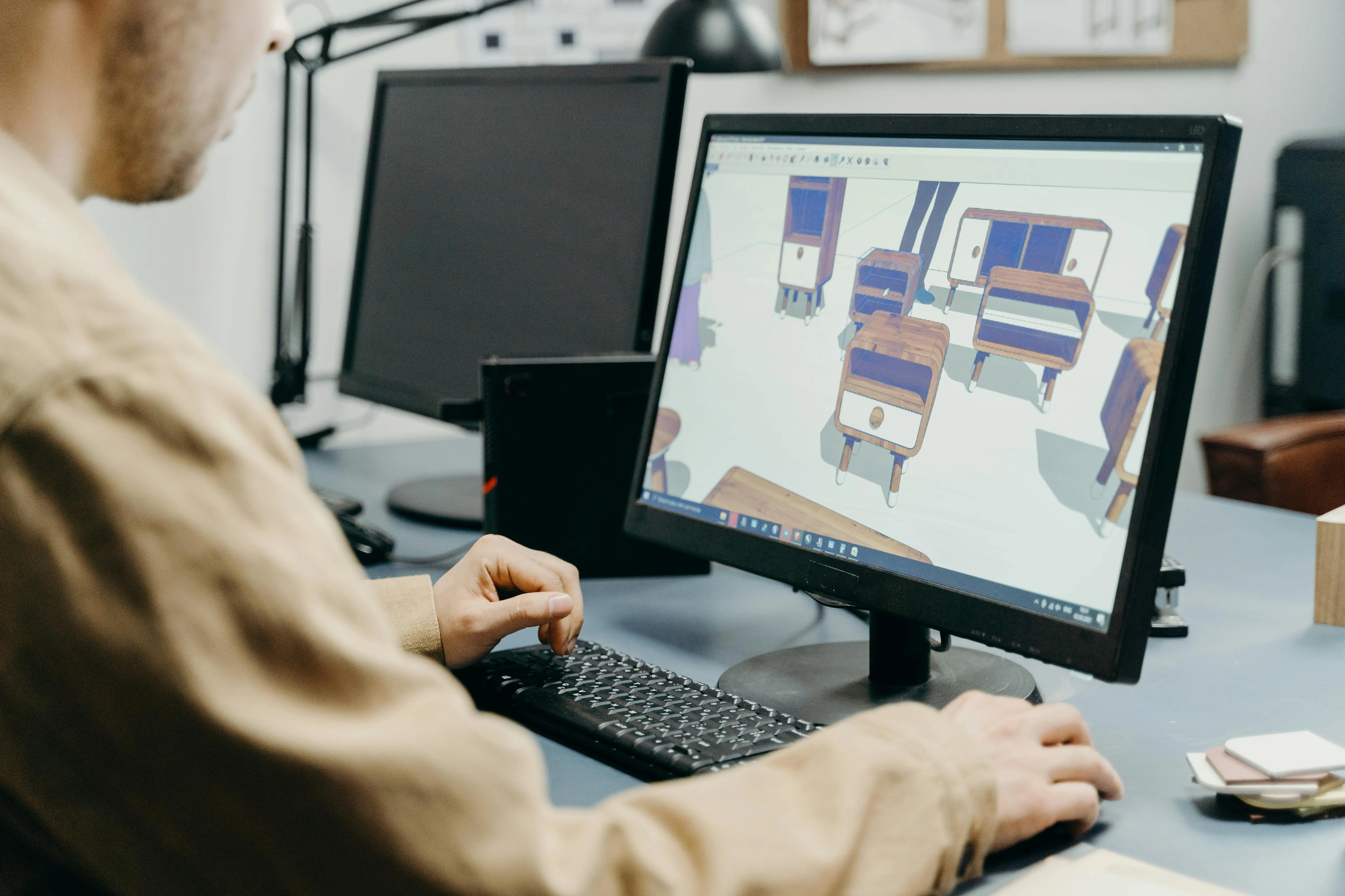 Designer working on 3D modeling software at a desk, creating wooden furniture prototypes on a computer screen, illustrating how 3D modeling can boost ROI and solve business challenges in product development